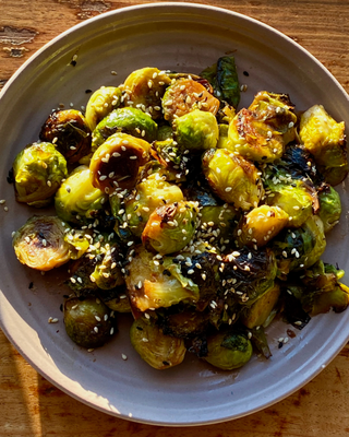 Bowl of honeynut squash miso brussel sprouts on a wood counter