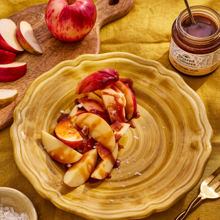 Plate of sliced apples covered in miso caramel sauce and salt and a jar of Shared Cultures Miso Caramel Sauce