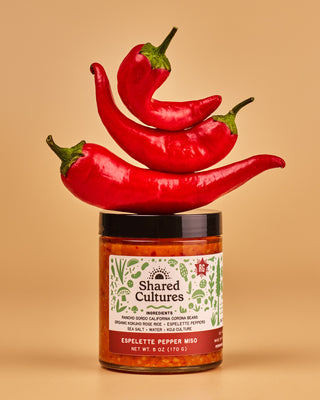 Jar of 'Shared Cultures' espelette pepper miso with three espelette peppers stacked above