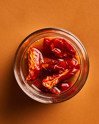 Open jar of preserved summer tomatoes