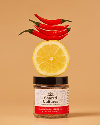 Jar of Shared Cultures Calabrian Chili Lemon Salt with chili peppers and lemon stacked above the jar.