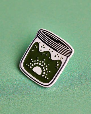 Up close of Shared Cultures Green Logo Jar Pin