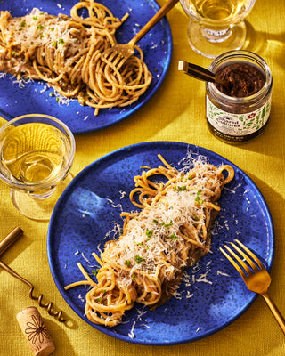 Two plates of Black Garlic Pasta plated and a jar of Shared Cultures Black Garlic Miso