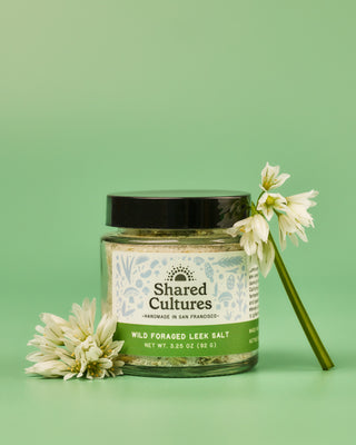 Jar of Shared Cultures Wild Foraged Leek Salt with leek flowers placed around