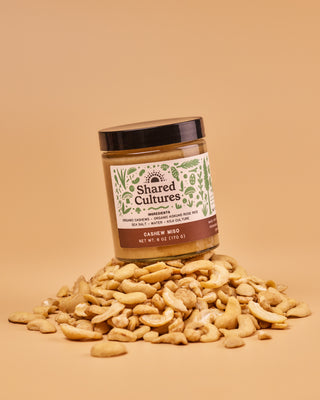 Jar of Shared Cultures Cashew Miso sitting on a pile of cashews